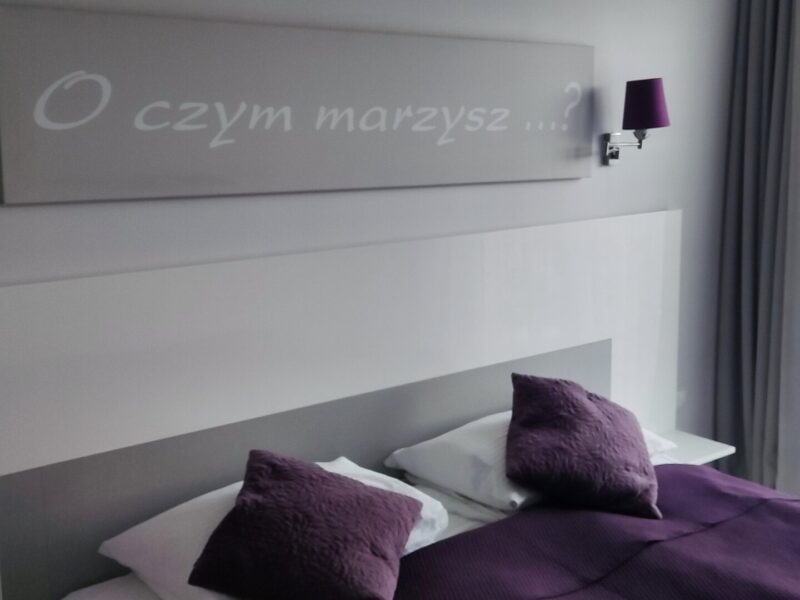Sypialnia z podwójnym łożem i dekoracją O czym marzysz na ścianie