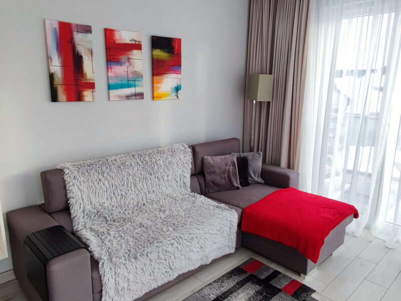 Jasny salon apartamentu Na Skarpie z rogową sofą i drzwiami balkonowymi